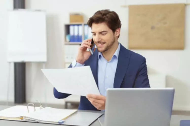 Businessman talking on phone, reviewing documents.