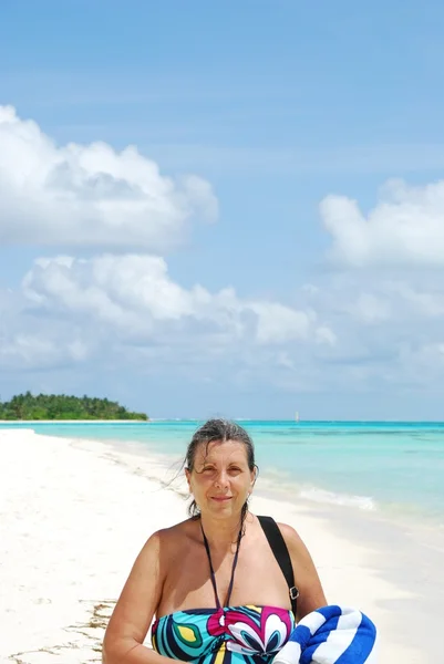 Woman on beach with colorful towel.