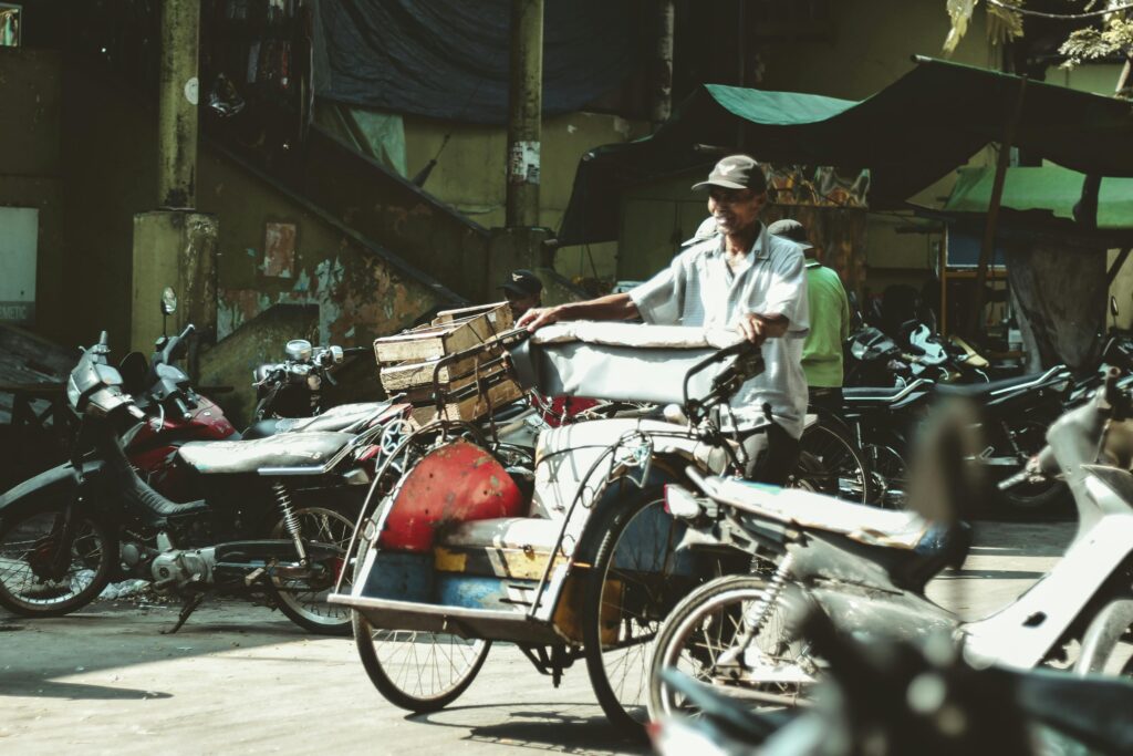 Man pushing cart through crowded street.